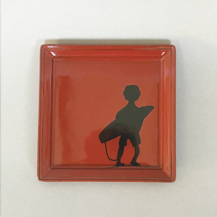 assiette revol en porcelaine noire et emaillée en rouge avec le surfeur