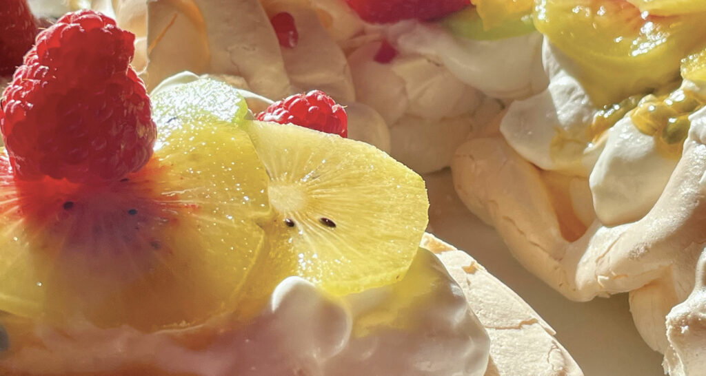 la pavlova Lauburu est en forme de croix basque et se décline avec ttrois variétés de kiwis, présentée sur un plat rond pays basque par assiettes et compagnie